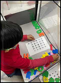 Young student working with colorful letters at his desk