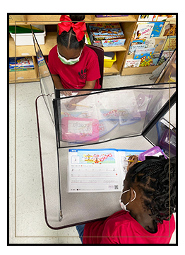 Two girls wearing red working at their desks