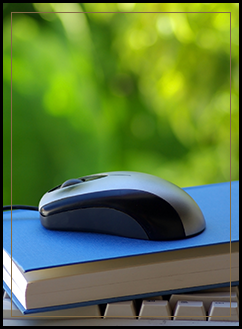 Computer mouse sitting on top of a book that is on top of a computer keyboard