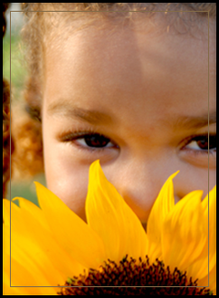 Female student hiding behind a sunflower