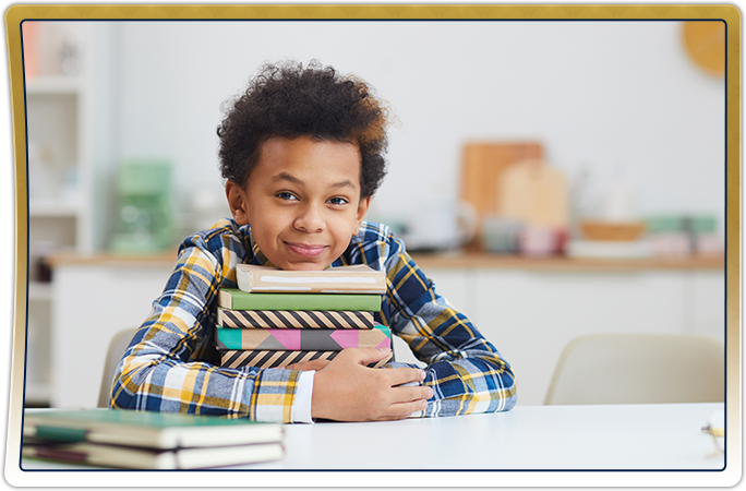 Happy elementary student sitting at a desk with books